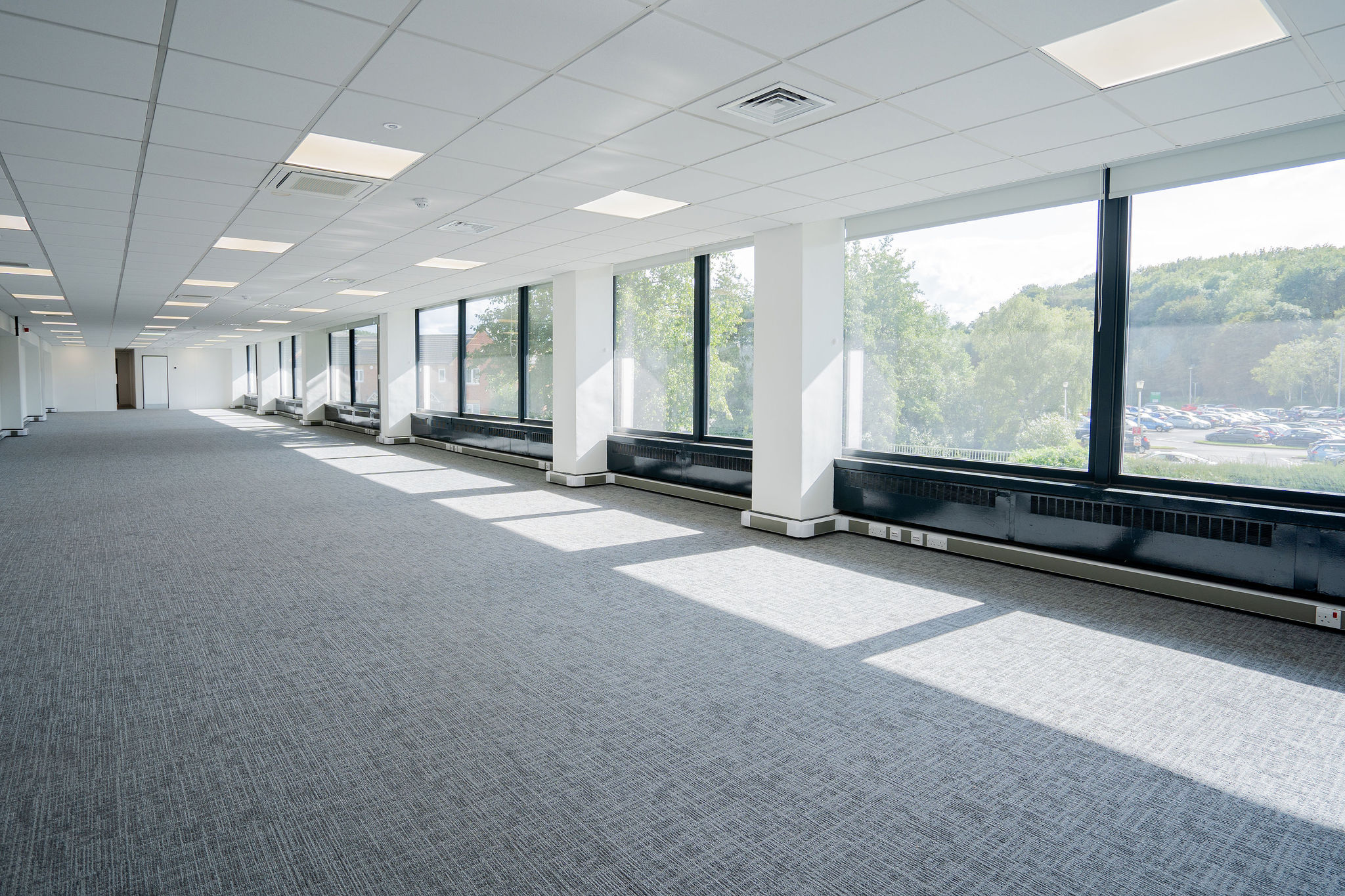 Office space hexagon tower large open plan office space with white ceilings grey carpets and large windows