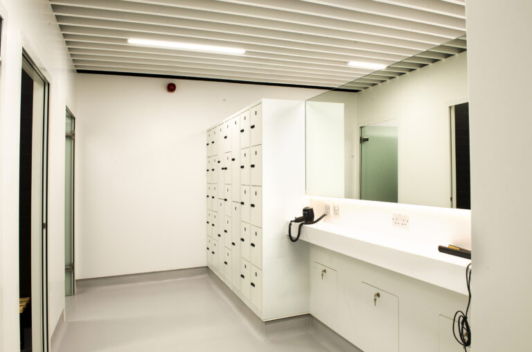 white locker room with hair dryers and showers