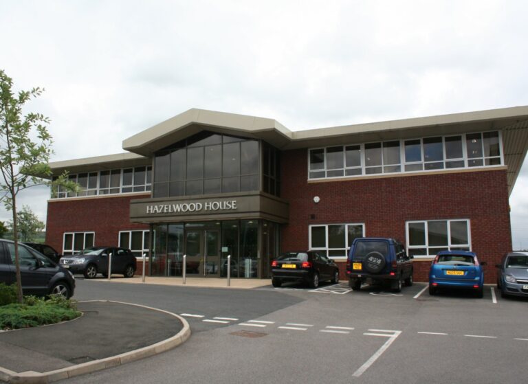 brown brick two storey office building with glass facade over entrance and hazelwood house signage
